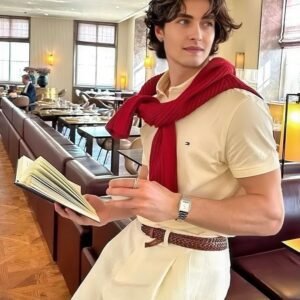 Preppy Knit-Layered Polo Outfit: A cream cotton polo paired with a burgundy sweater draped over the shoulders, styled with pleated ivory trousers and a braided leather belt.